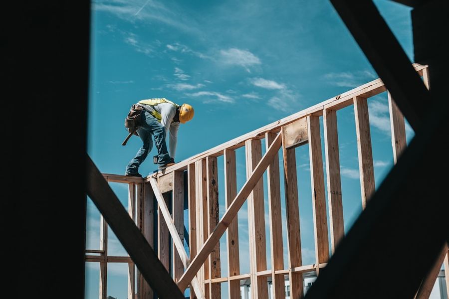 A construction worker in a hard hat on a building frame